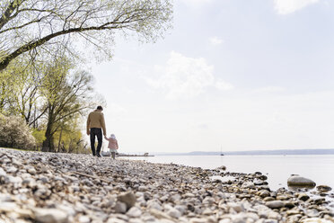 Deutschland, Bayern, Herrsching, Vater und Tochter gehen am Kieselstrand am Seeufer spazieren - DIGF06743