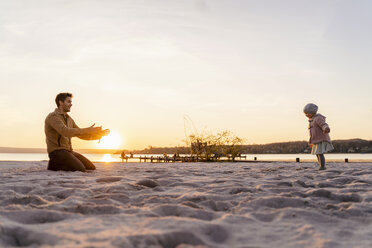 Germany, Bavaria, Herrsching, father and daughter playing on the beach at sunset - DIGF06756