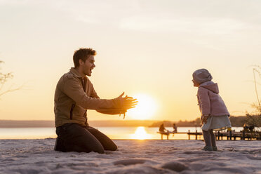 Deutschland, Bayern, Herrsching, Vater und Tochter spielen bei Sonnenuntergang am Strand - DIGF06757