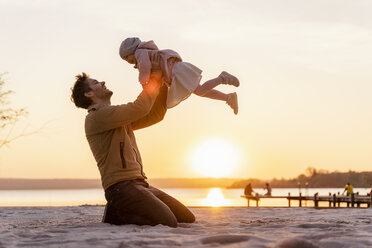 Germany, Bavaria, Herrsching, father and daughter playing on the beach at sunset - DIGF06758