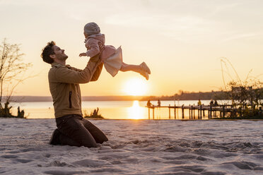Germany, Bavaria, Herrsching, father and daughter playing on the beach at sunset - DIGF06759