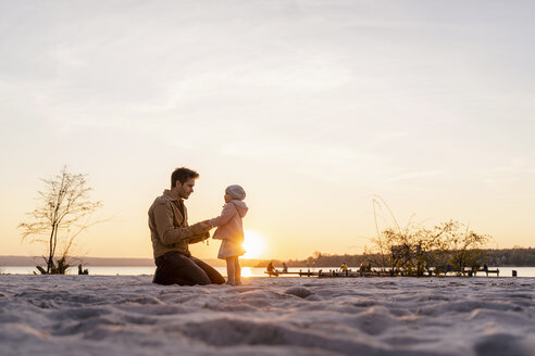 Deutschland, Bayern, Herrsching, Vater und Tochter spielen bei Sonnenuntergang am Strand - DIGF06760