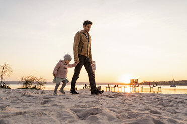 Deutschland, Bayern, Herrsching, Vater und Tochter gehen bei Sonnenuntergang am Strand spazieren - DIGF06765