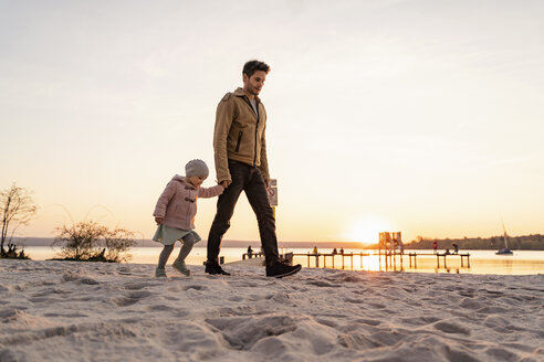 Deutschland, Bayern, Herrsching, Vater und Tochter gehen bei Sonnenuntergang am Strand spazieren - DIGF06765