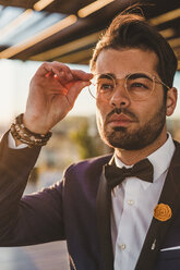 Portrait of stylish man on roof terrace at sunset - FBAF00369