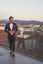 Italy, Florence, Portrait of stylish man on roof terrace at sunset - FBAF00373