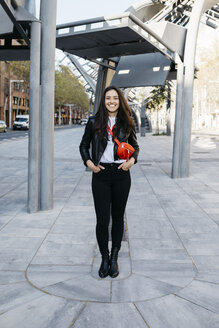Glückliche junge Frau mit einer roten Hüfttasche in der Stadt - JRFF03084