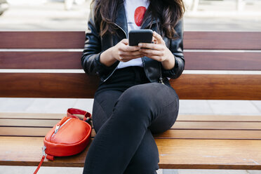 Young woman sitting on a bench, using smartphone - JRFF03087