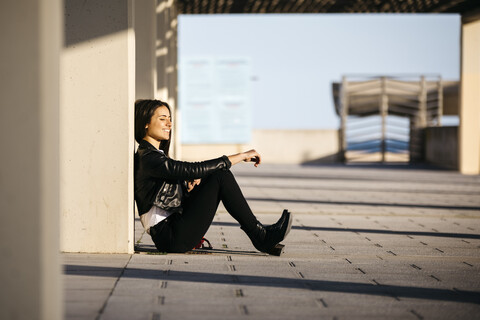 Junge Frau sitzt auf dem Boden und genießt das Sonnenlicht, lizenzfreies Stockfoto