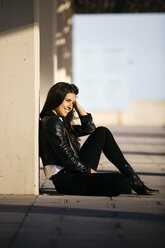 Young woman sitting on floor, enjoying sunlight - JRFF03123