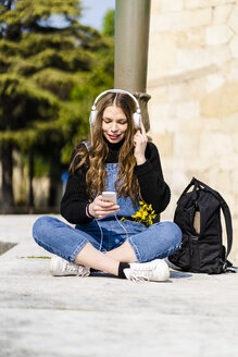 Junge Frau mit Smartphone und Kopfhörern in Verona - GIOF06261