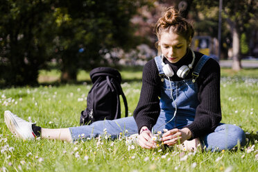 Young woman picking daisies in a park - GIOF06270