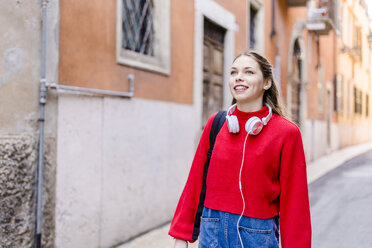 Junge Frau mit rotem Pullover und Kopfhörern in Verona - GIOF06288