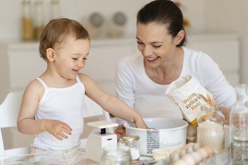 Glückliche Mutter und kleine Tochter machen einen Kuchen zusammen in der Küche zu Hause - DIGF06766