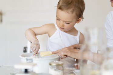 Mutter und kleine Tochter backen zusammen einen Kuchen in der Küche zu Hause - DIGF06767