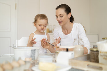 Mother and little daughter making a cake together in kitchen at home - DIGF06770