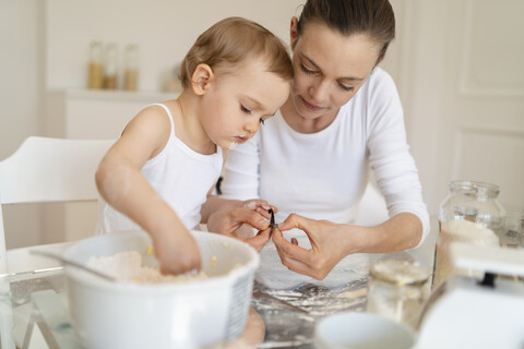 Mutter und kleine Tochter backen zusammen einen Kuchen in der Küche zu Hause, lizenzfreies Stockfoto