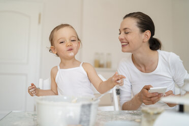 Glückliche Mutter und kleine Tochter machen einen Kuchen zusammen in der Küche zu Hause - DIGF06775