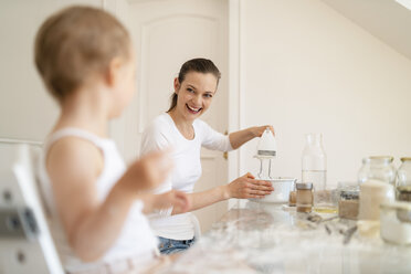 Happy mother and little daughter making a cake together in kitchen at home - DIGF06778