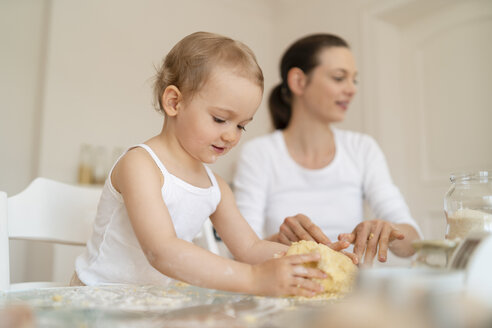 Mutter und kleine Tochter backen zusammen einen Kuchen in der Küche zu Hause - DIGF06781