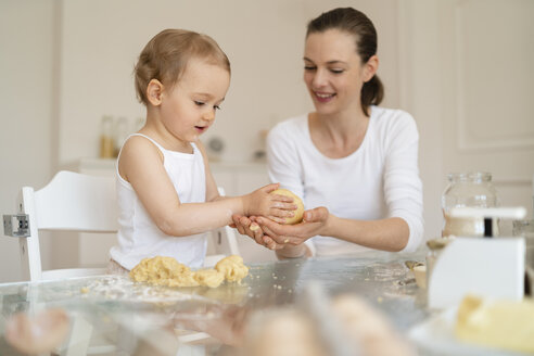 Mutter und kleine Tochter backen zusammen einen Kuchen in der Küche zu Hause - DIGF06782
