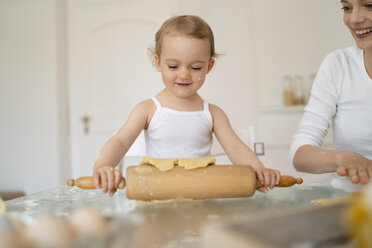 Mutter und kleine Tochter mit Teigrolle machen einen Kuchen zusammen in der Küche zu Hause - DIGF06785