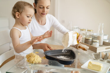 Mutter und kleine Tochter backen zusammen einen Kuchen in der Küche zu Hause - DIGF06788