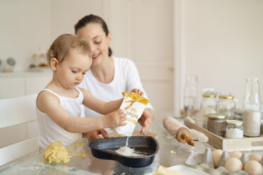 Mutter und kleine Tochter backen zusammen einen Kuchen in der Küche zu Hause - DIGF06789