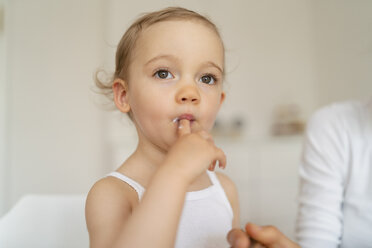 Little girl licking her finger while making a cake in kitchen at home - DIGF06790