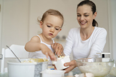 Mutter und kleine Tochter backen zusammen einen Kuchen in der Küche zu Hause - DIGF06791