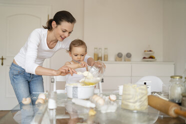 Mutter und kleine Tochter backen zusammen einen Kuchen in der Küche zu Hause - DIGF06793
