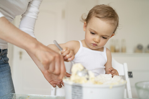 Mutter und kleine Tochter backen zusammen einen Kuchen in der Küche zu Hause, lizenzfreies Stockfoto