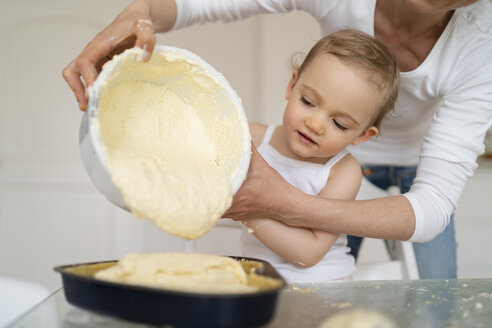 Mutter und kleine Tochter backen gemeinsam einen Kuchen und gießen Teig in eine Backform - DIGF06796