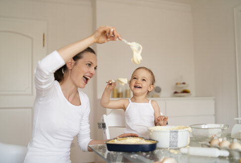 Glückliche Mutter und kleine Tochter machen einen Kuchen zusammen in der Küche zu Hause - DIGF06798