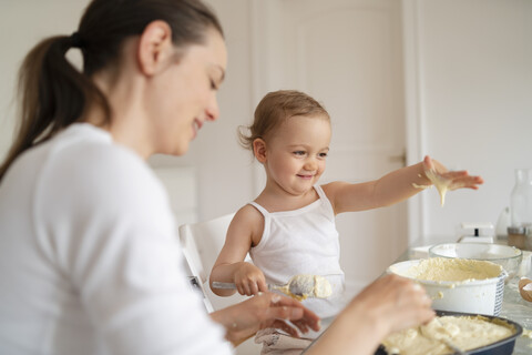 Mutter und kleine Tochter backen zusammen einen Kuchen in der Küche zu Hause, lizenzfreies Stockfoto