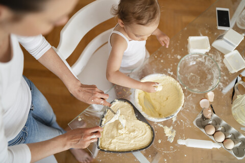 Draufsicht auf Mutter und kleine Tochter, die zusammen in der Küche zu Hause einen Kuchen backen, lizenzfreies Stockfoto