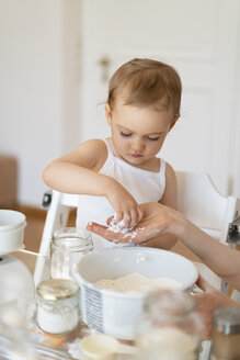 Mutter und kleine Tochter backen zusammen einen Kuchen in der Küche zu Hause - DIGF06807