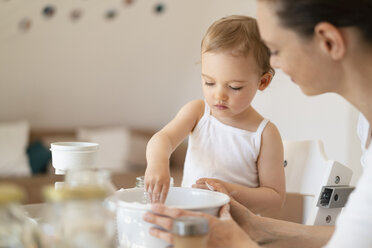 Mutter und kleine Tochter backen zusammen einen Kuchen in der Küche zu Hause - DIGF06808