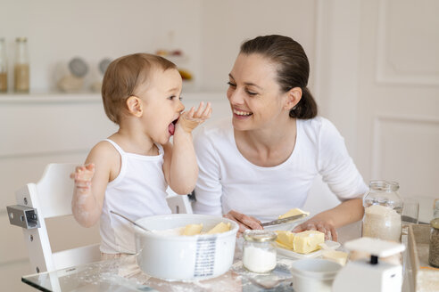 Glückliche Mutter und kleine Tochter machen einen Kuchen zusammen in der Küche zu Hause - DIGF06811