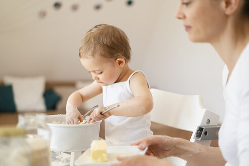 Mutter und kleine Tochter backen zusammen einen Kuchen in der Küche zu Hause - DIGF06812