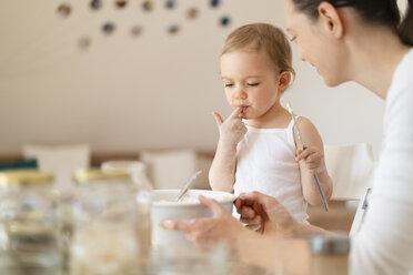 Mutter und kleine Tochter backen zusammen einen Kuchen in der Küche zu Hause - DIGF06813