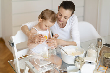 Mother and little daughter making a cake together in kitchen at home - DIGF06815