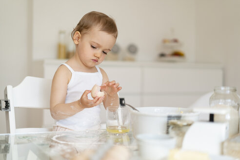 Mädchen macht einen Kuchen in der Küche zu Hause knacken ein Ei - DIGF06816