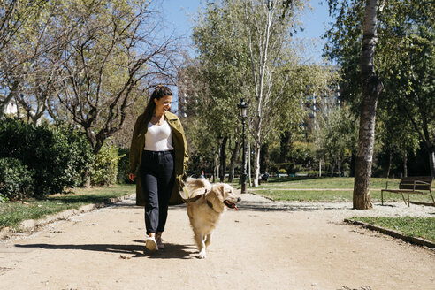 Glückliche Frau geht im Stadtpark mit ihrem Labrador Retriever spazieren - JRFF03145