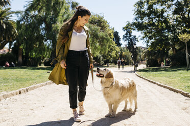Glückliche Frau geht im Stadtpark mit ihrem Labrador Retriever spazieren - JRFF03146