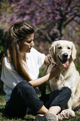 Frau und Labrador Retriever sitzen auf einer Wiese im Stadtpark - JRFF03151