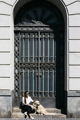 Woman sitting on stairs with her Labrador Retriever enjoying sunlight - JRFF03160