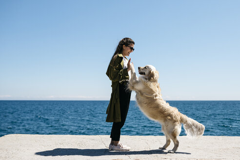 Laughing woman playing with her Labrador Retriever on a dock - JRFF03167