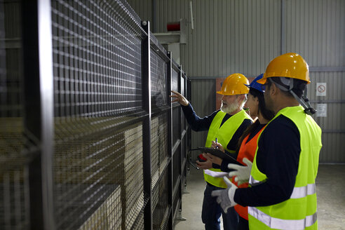 Arbeiter stehen am Gitter in der Fabrik und unterhalten sich - ZEDF02232