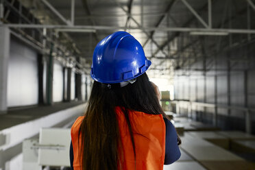 Rear view of female worker on the phone in factory warehouse - ZEDF02242